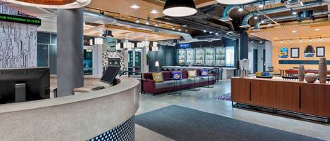 A modern lobby with a reception desk, seating area, and bar.