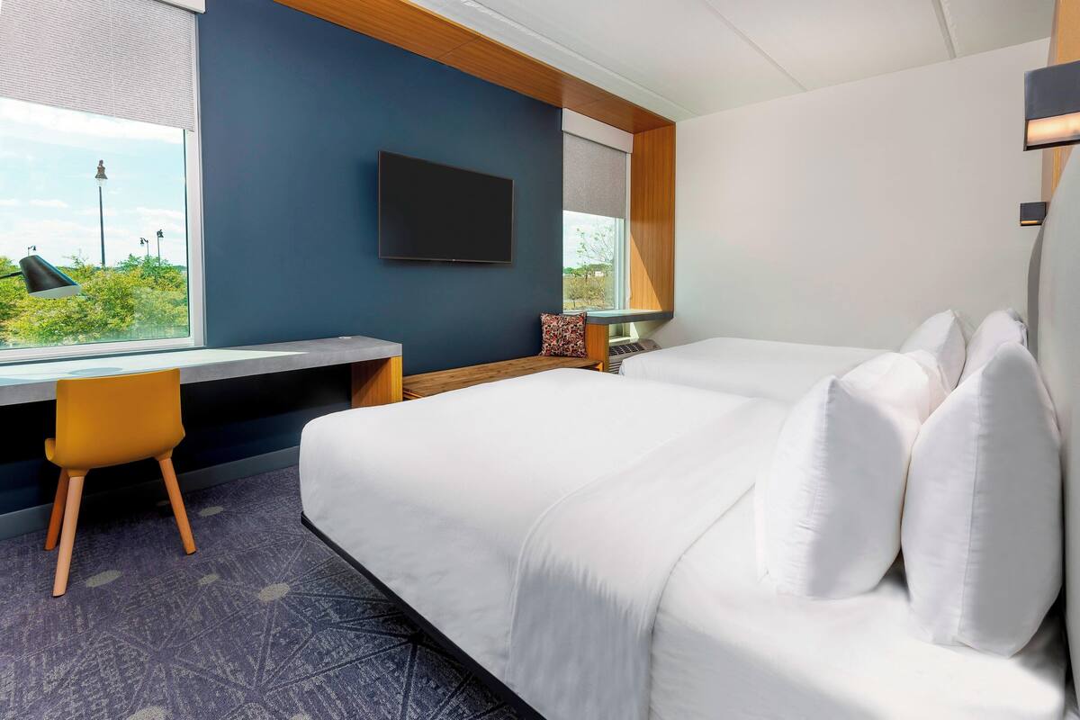 Une chambre d’hôtel avec un grand lit, un bureau, une chaise et un téléviseur.