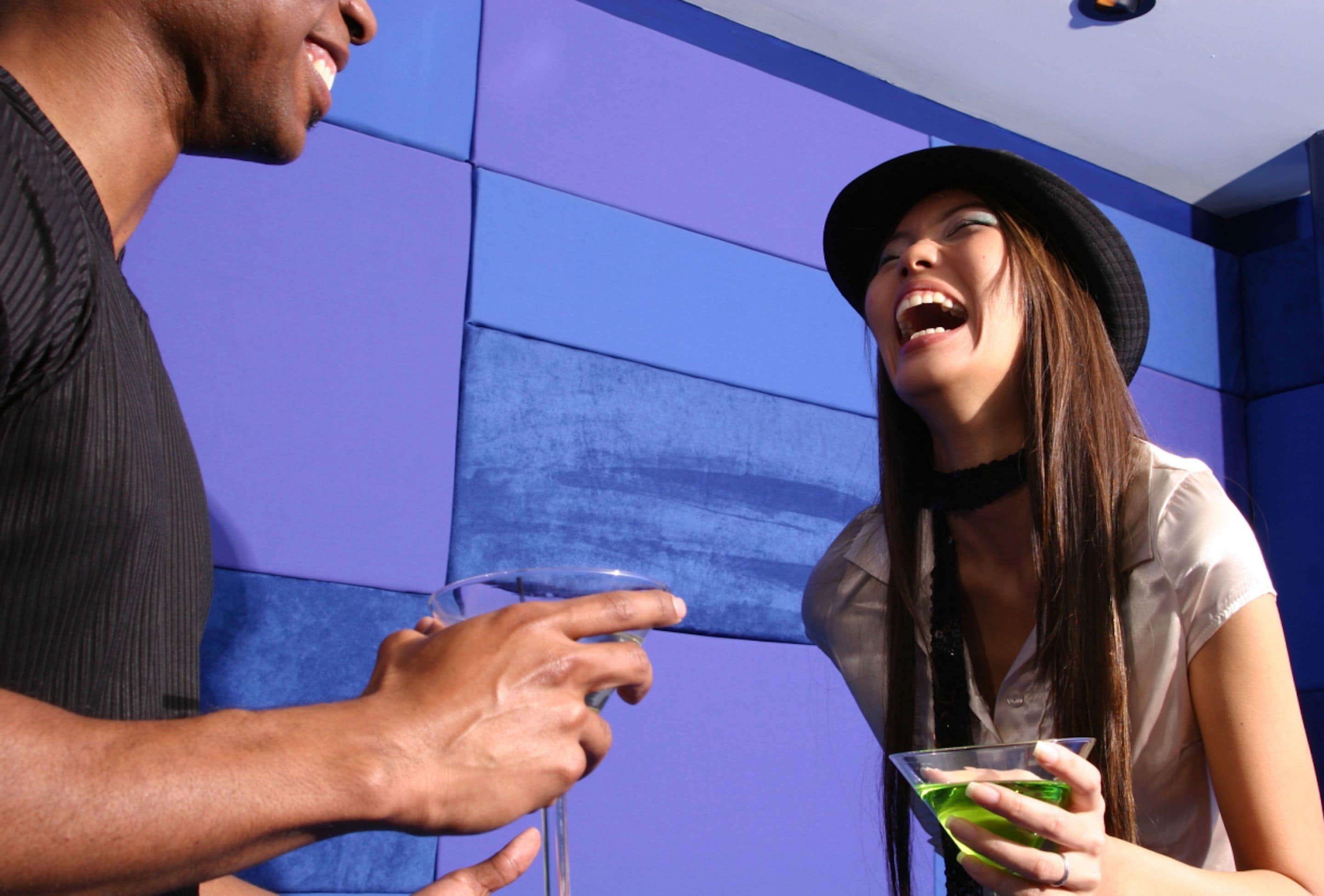 A man and a woman holding drinks in a room with blue walls.