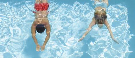 A swimming pool with clear water and two swimmers.