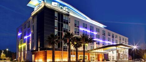 A modern hotel with a prominent 'ab' sign, large windows, and a well-lit entrance.
