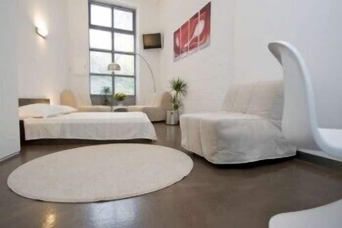 Une chambre moderne et minimaliste, dotée de deux lits, d’un grand tapis rond et d’une chaise blanche originale.