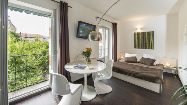 Une chambre à coucher moderne avec un lit, une table de chevet et un téléviseur fixé au mur.