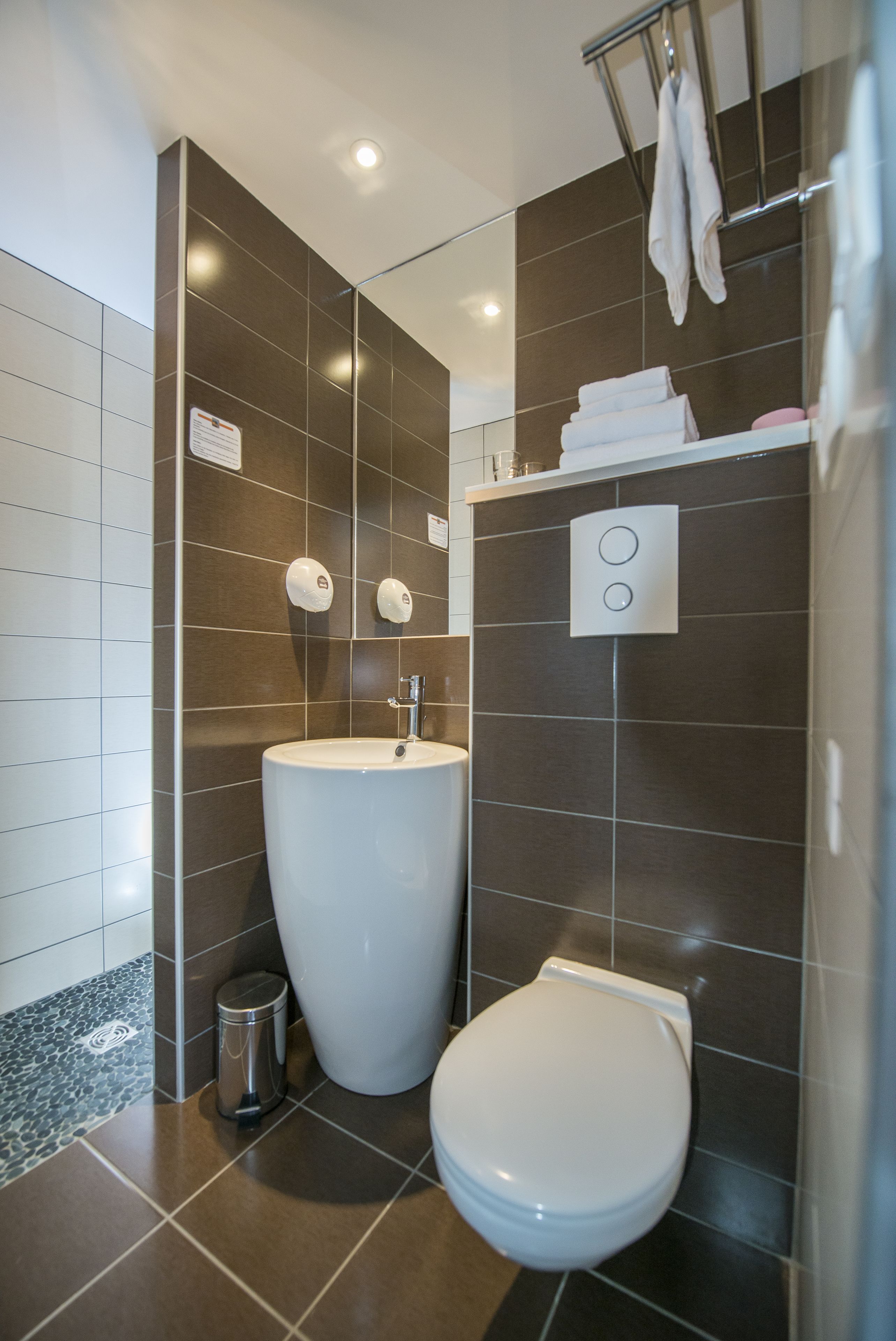 A modern bathroom with a large white sink, a toilet, and a towel rack.