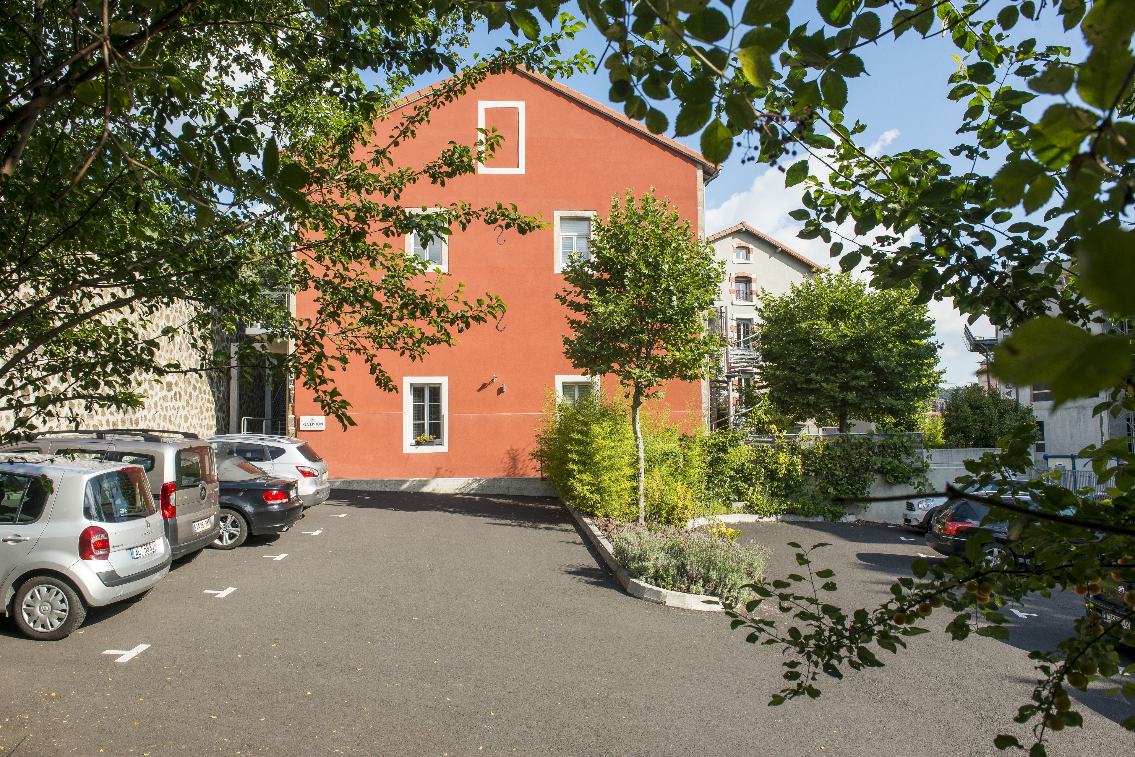 A parking lot with several cars and a red building in the background.
