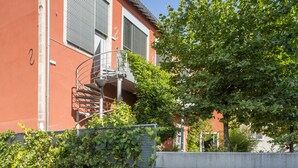 Un bâtiment doté d’un escalier en colimaçon, d’une façade rouge et d’un arbre devant.