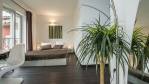 Une chambre à coucher moderne avec un lit, une table de chevet et une grande plante en pot.