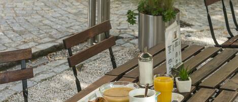 A wooden bench with a tray containing a croissant, a cup of coffee, and a glass of orange juice.