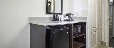 Una kitchenette compacta con refrigerador, microondas y cafetera.