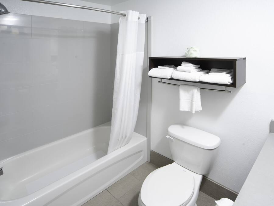 Een badkamer met een bad, douche, toilet en een plank met handdoeken.