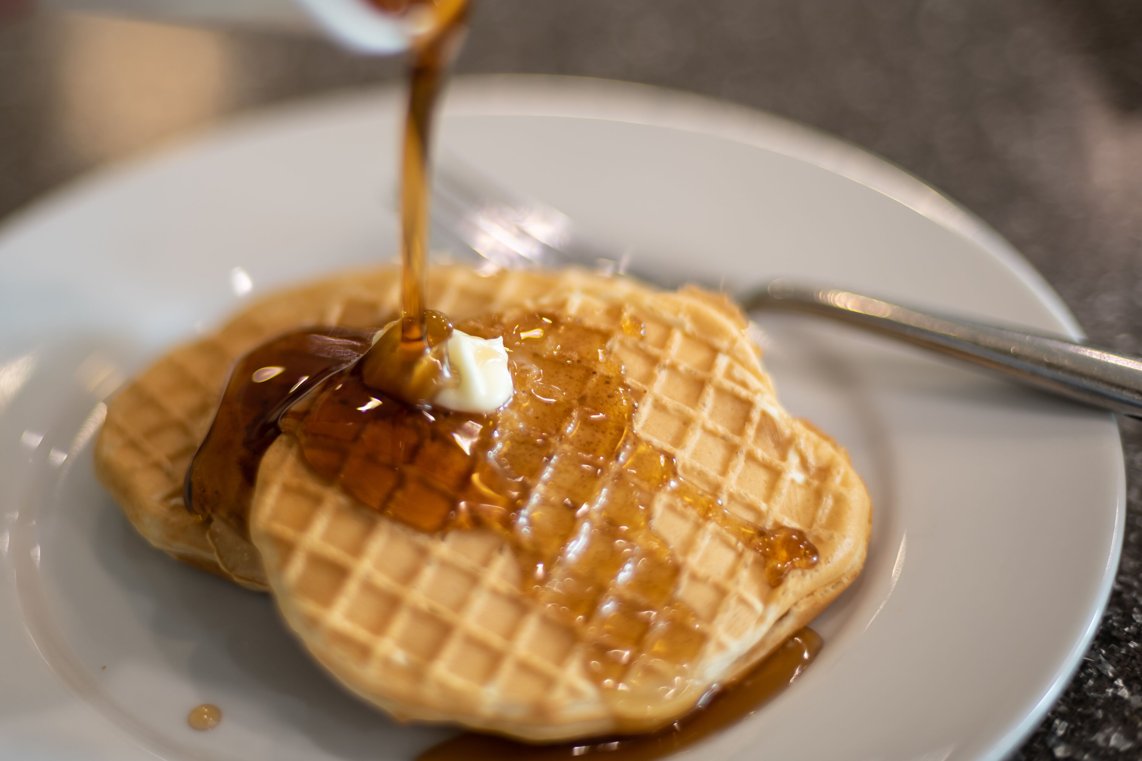 A waffle with syrup and butter on a plate.