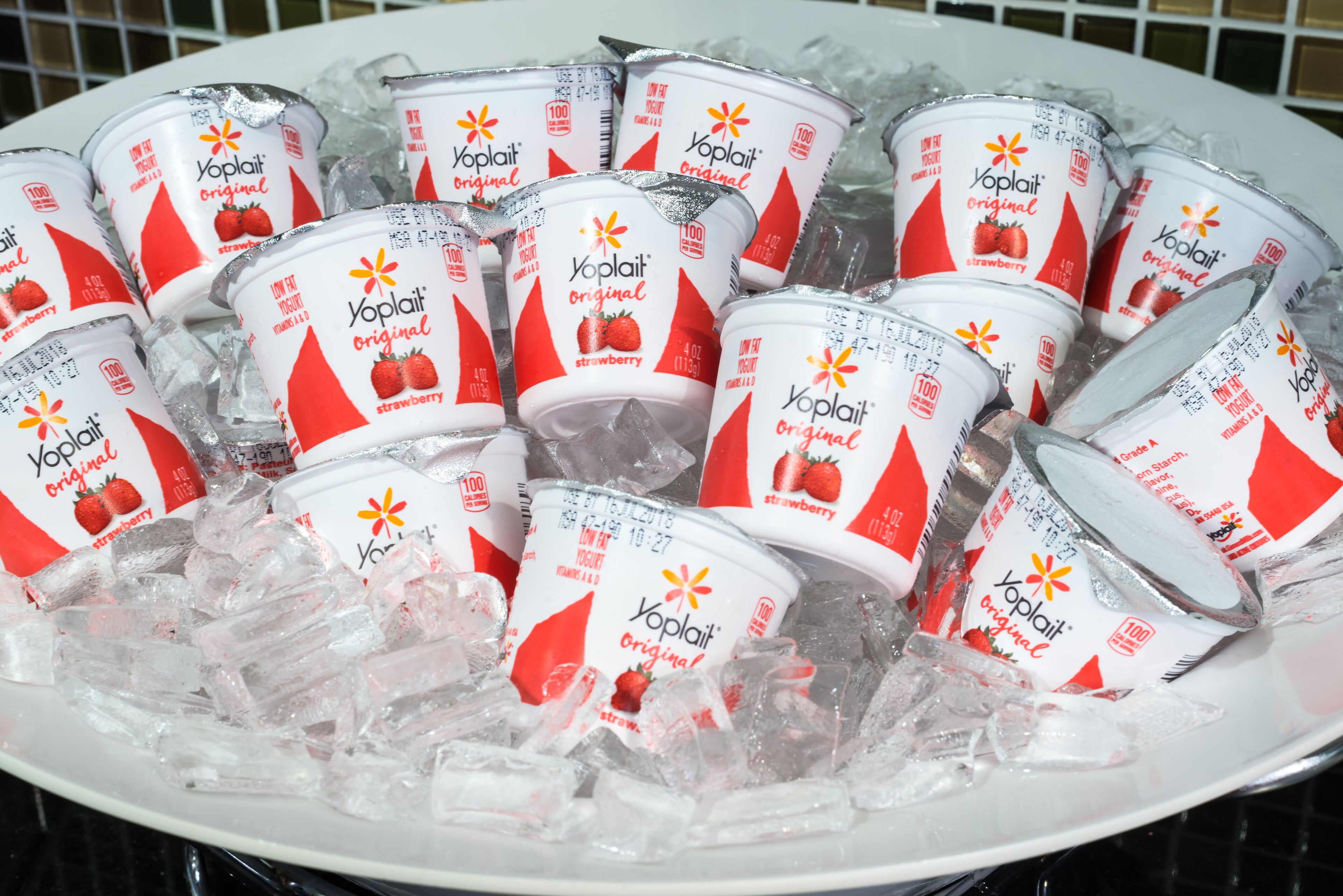 Lautasella on Yoplait-merkkisiä, alkuperäisen reseptin mukaisia mansikkanjogurttituotteita, jotka on tarjoiltu jäiden päällä.