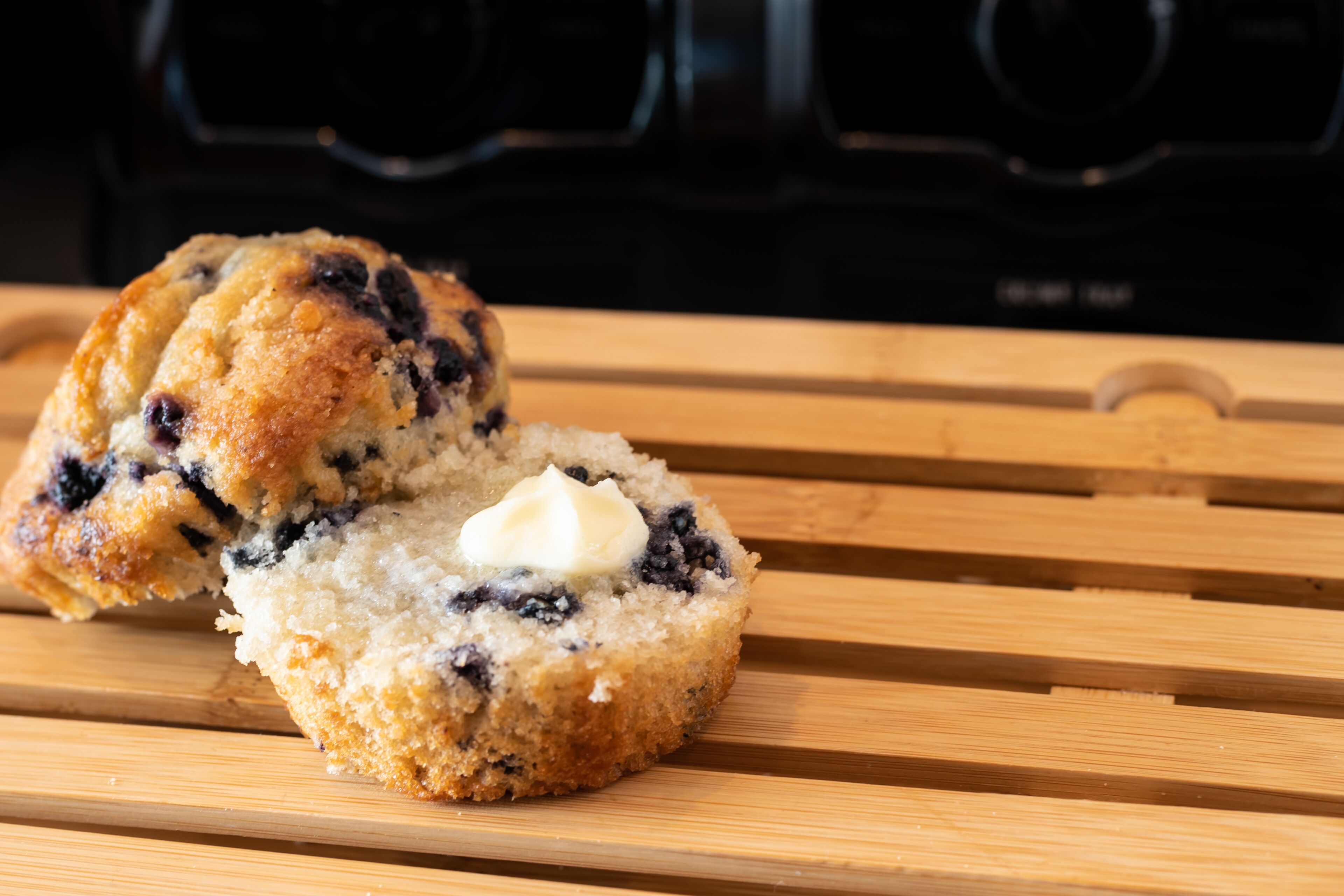 A muffin with a dollop of butter on a wooden surface.