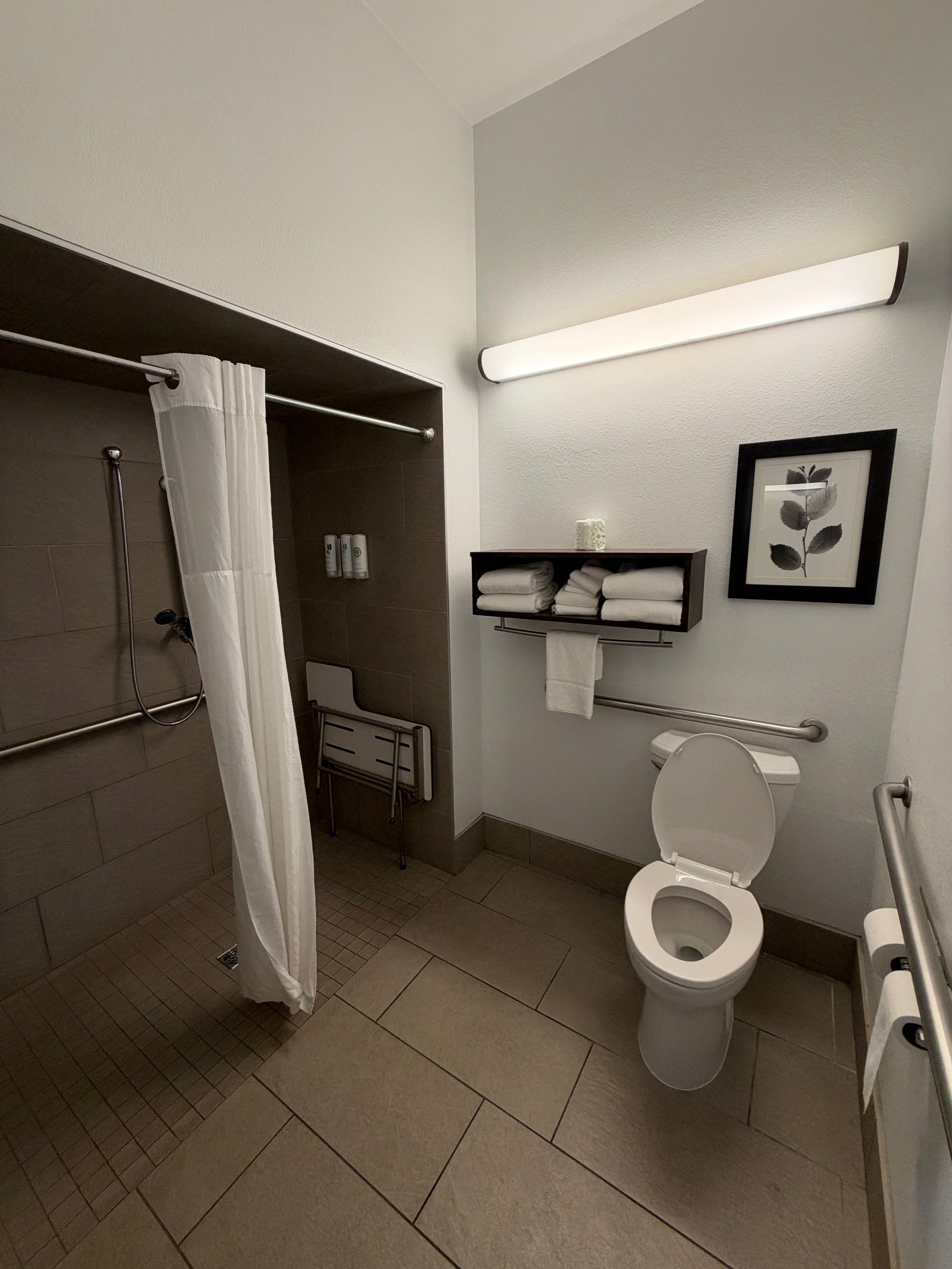 Un baño moderno con ducha, inodoro y un estante con toallas.