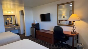 A hotel room with two beds, a desk, a chair, a TV, a mirror, a lamp, and a trash bin. - Canyonlands Motor Inn (Monticello)