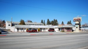 A motel with a large parking lot, a covered parking area, and a sign for Canyonlands Motor Inn. - Canyonlands Motor Inn (Monticello)