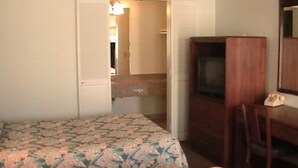 A room with two beds, a desk with a telephone, and a television. - Hometown Inn Galion (Galion)