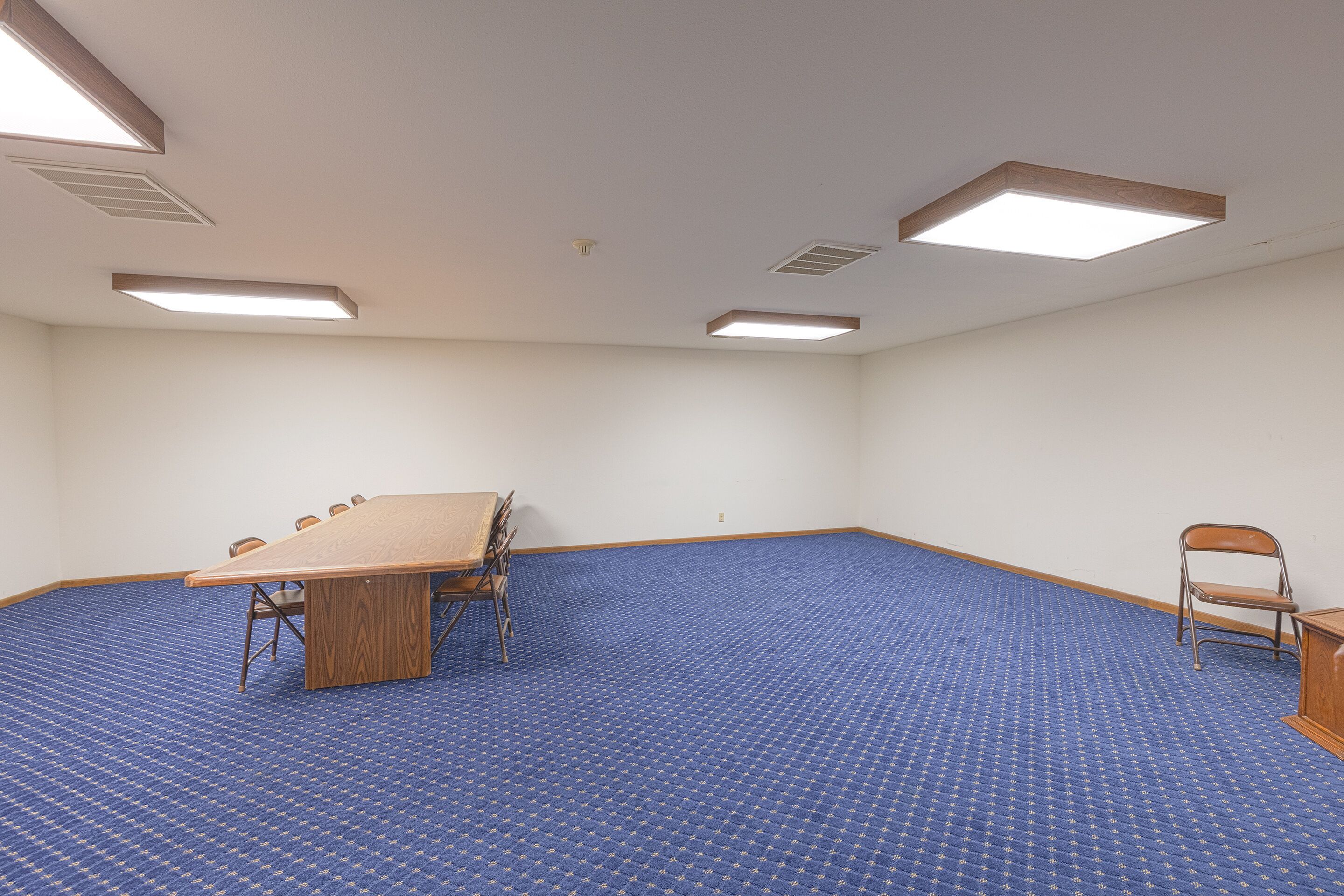 A conference room with a large table, chairs, and a blue carpet.