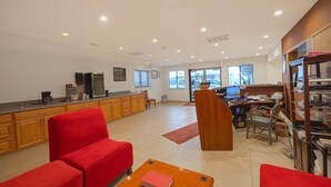 Un salón espacioso con cocina, un sofá rojo, una mesa de centro de madera y una estantería.