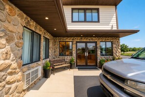 A stone exterior with a wooden bench, a car parked in front, and a building entrance with a sign reading 'Harlan Inn & Suites'.