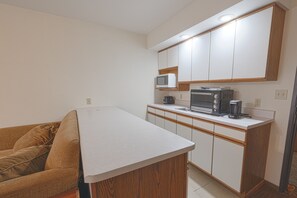 A compact kitchen with white cabinets, a microwave, a coffee maker, and a toaster.