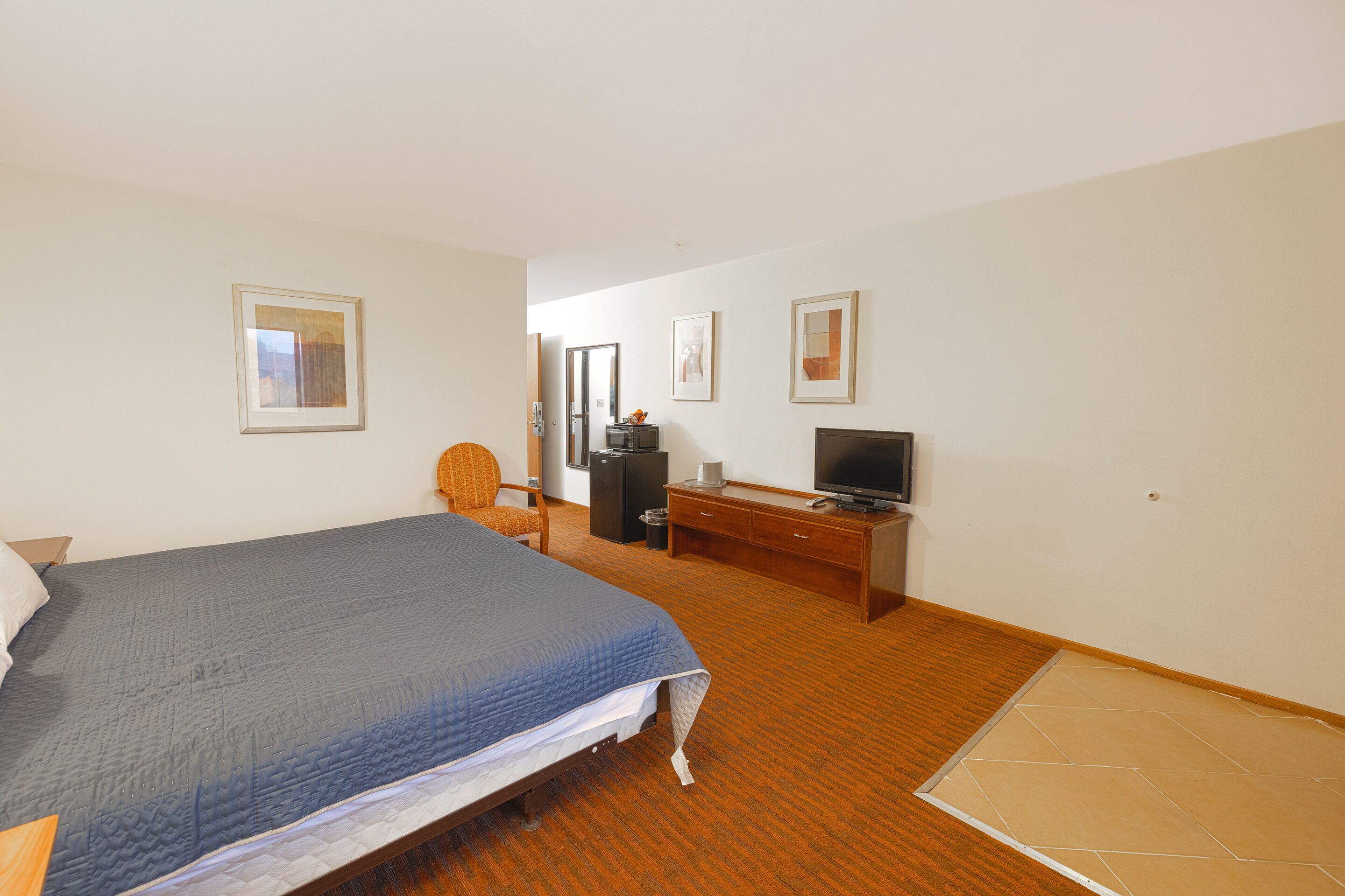 A hotel room with a bed, a television, a desk, and a chair.