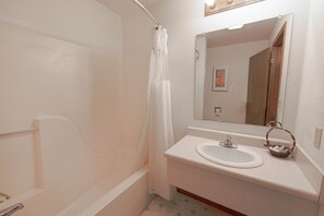 A bathroom with a bathtub, a sink, and a mirror.