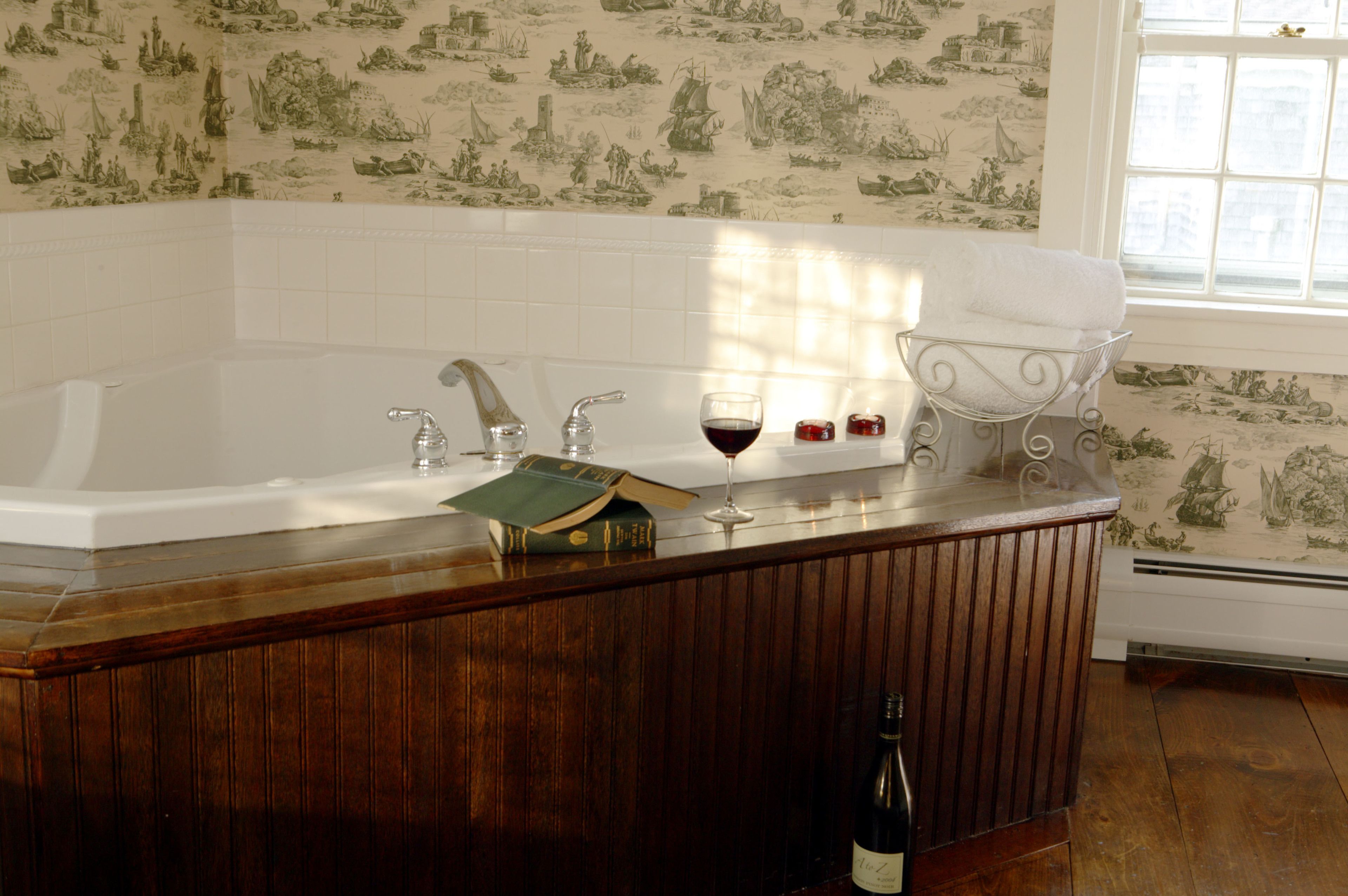 A bathroom with a bathtub, a vanity with a mirror, and a window.