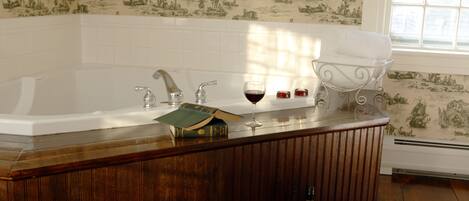 A bathroom with a bathtub, a vanity with a mirror, and a window.