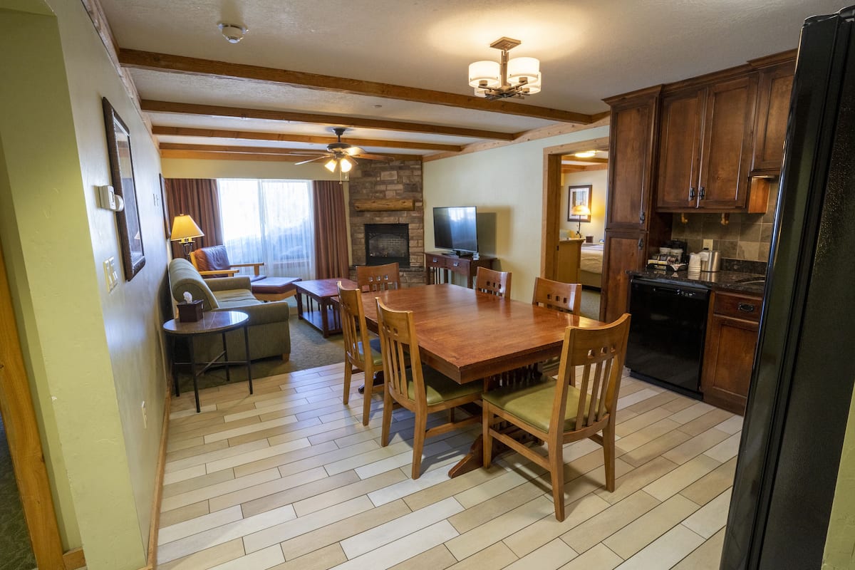 A spacious living room with a wooden dining table, comfortable seating, a fireplace, and a television.