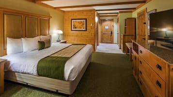 Quarto de hotel com uma cama grande, cabeceira de madeira, televisão e armário de madeira.