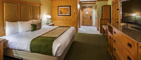 Une chambre d’hôtel avec un grand lit, une tête de lit en bois, une télévision et une armoire en bois.