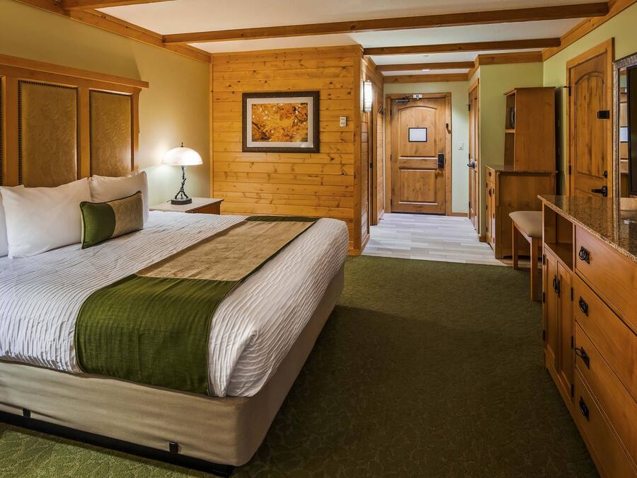 Quarto de hotel com uma cama grande, cabeceira de madeira, televisão e armário de madeira.