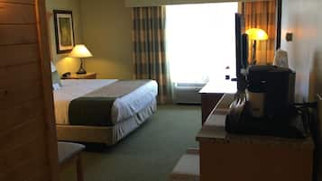 Une chambre d’hôtel avec un lit, un bureau, une lampe et une vue sur l’extérieur.