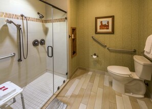 A bathroom with a glass shower enclosure, a toilet, a handrail, and a framed picture on the wall. - Brian Head Lodge (Brian Head)