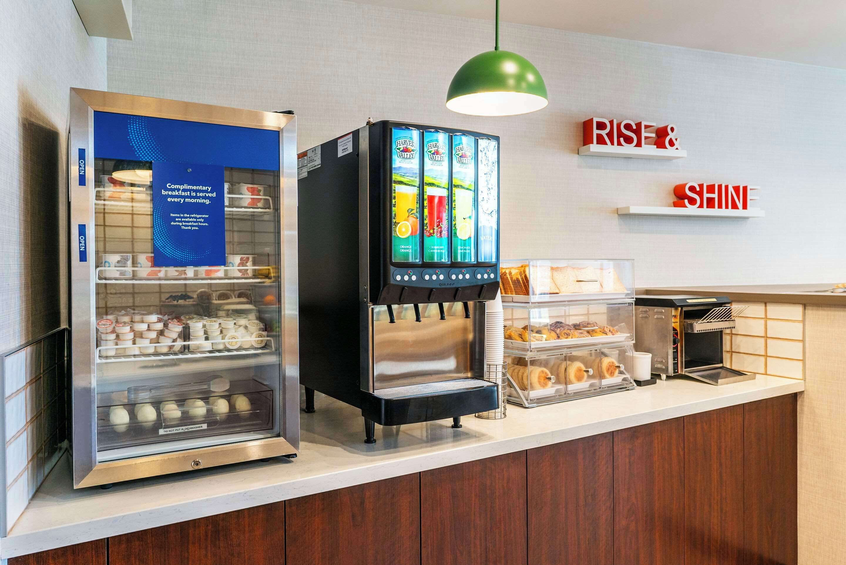A breakfast bar with a refrigerated display case, a beverage dispenser, and a toaster.