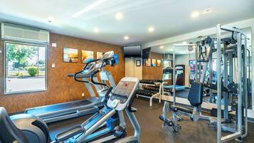 A gym with treadmills, weight machines, and dumbbells.