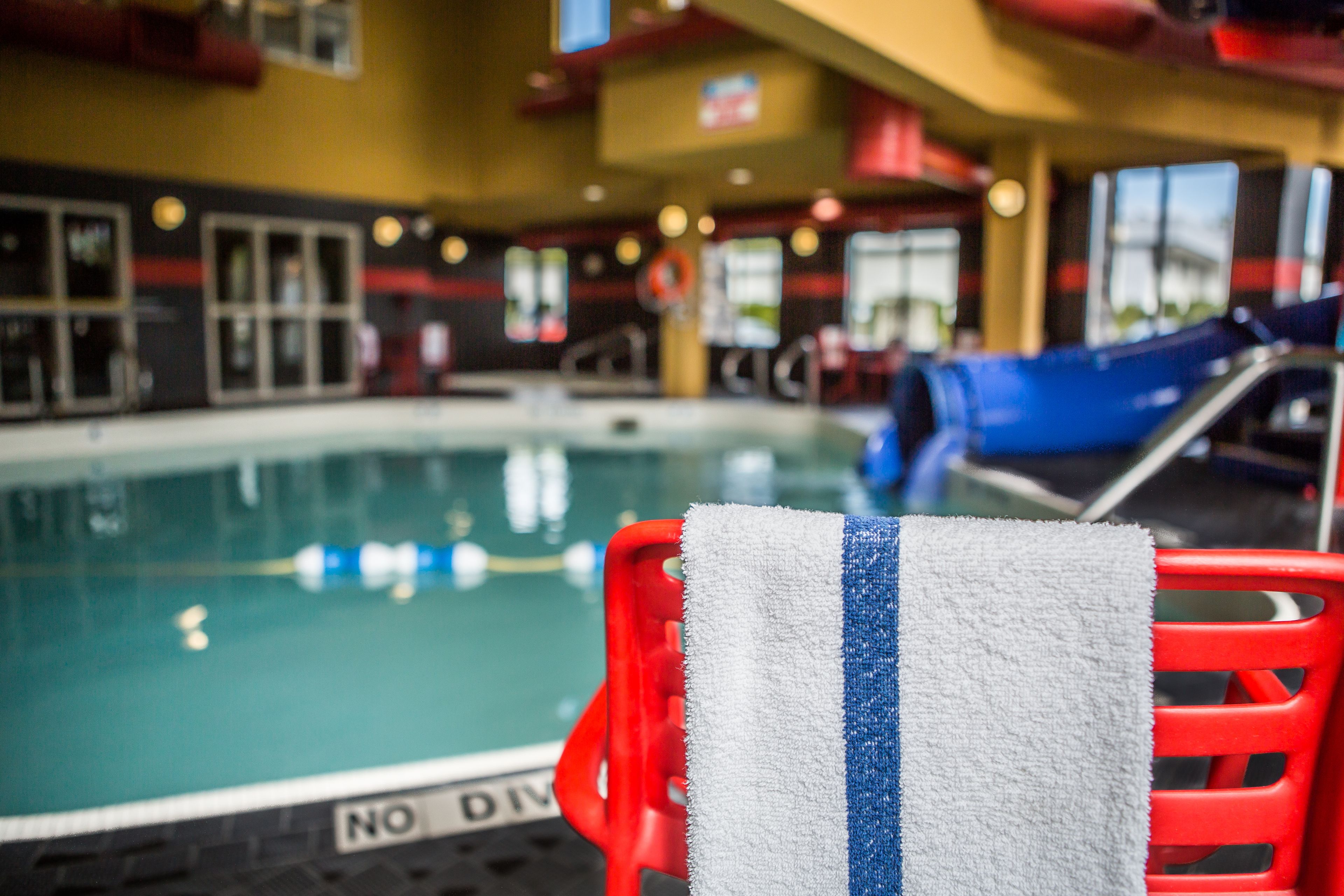 A pool area with a red chair and a towel.