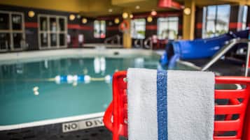 A pool area with a red chair and a towel.