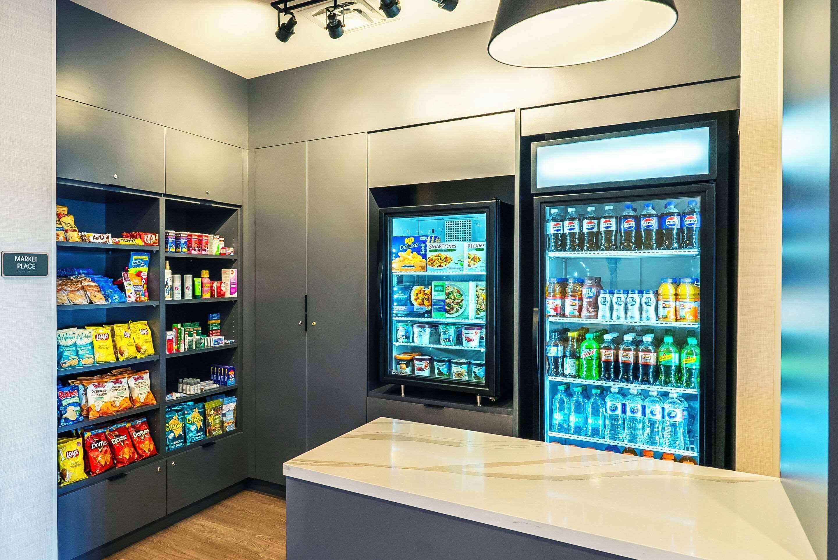 Un espace de libre-service où l’on peut trouver des en-cas et des boissons, avec des étagères remplies de chips, de biscuits et de bouteilles d’eau.