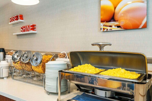 A buffet setup with various food items and a motivational sign on the wall.