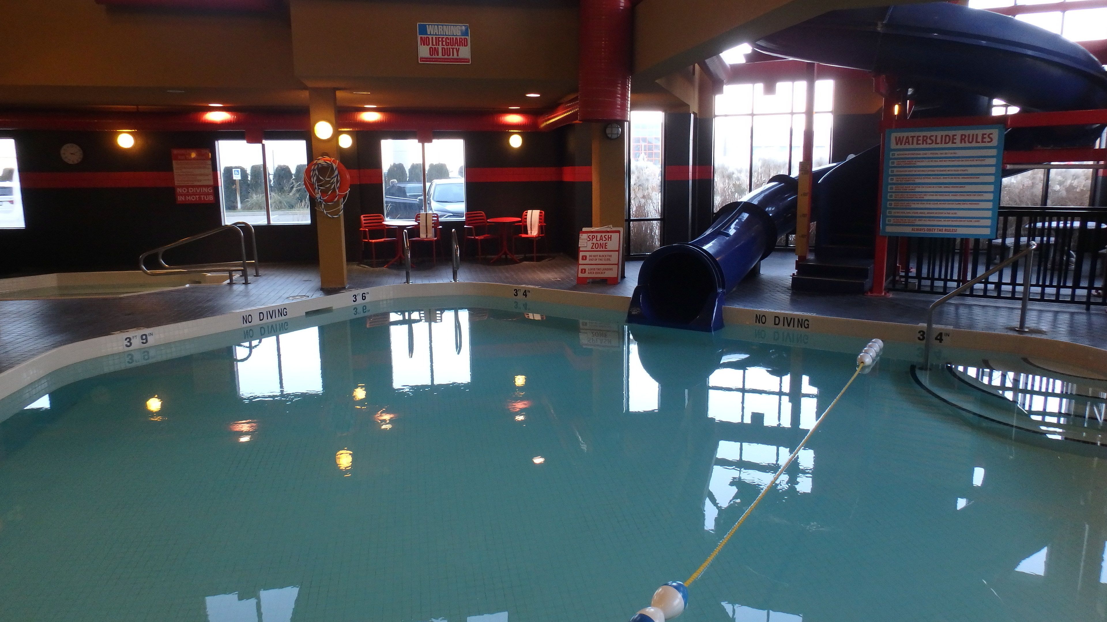 An indoor swimming pool with no diving signs, a splash zone, and a waterslide.
