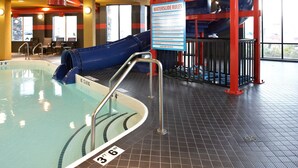 Piscina interior con múltiples toboganes y un cartel que enumera las reglas de los toboganes.