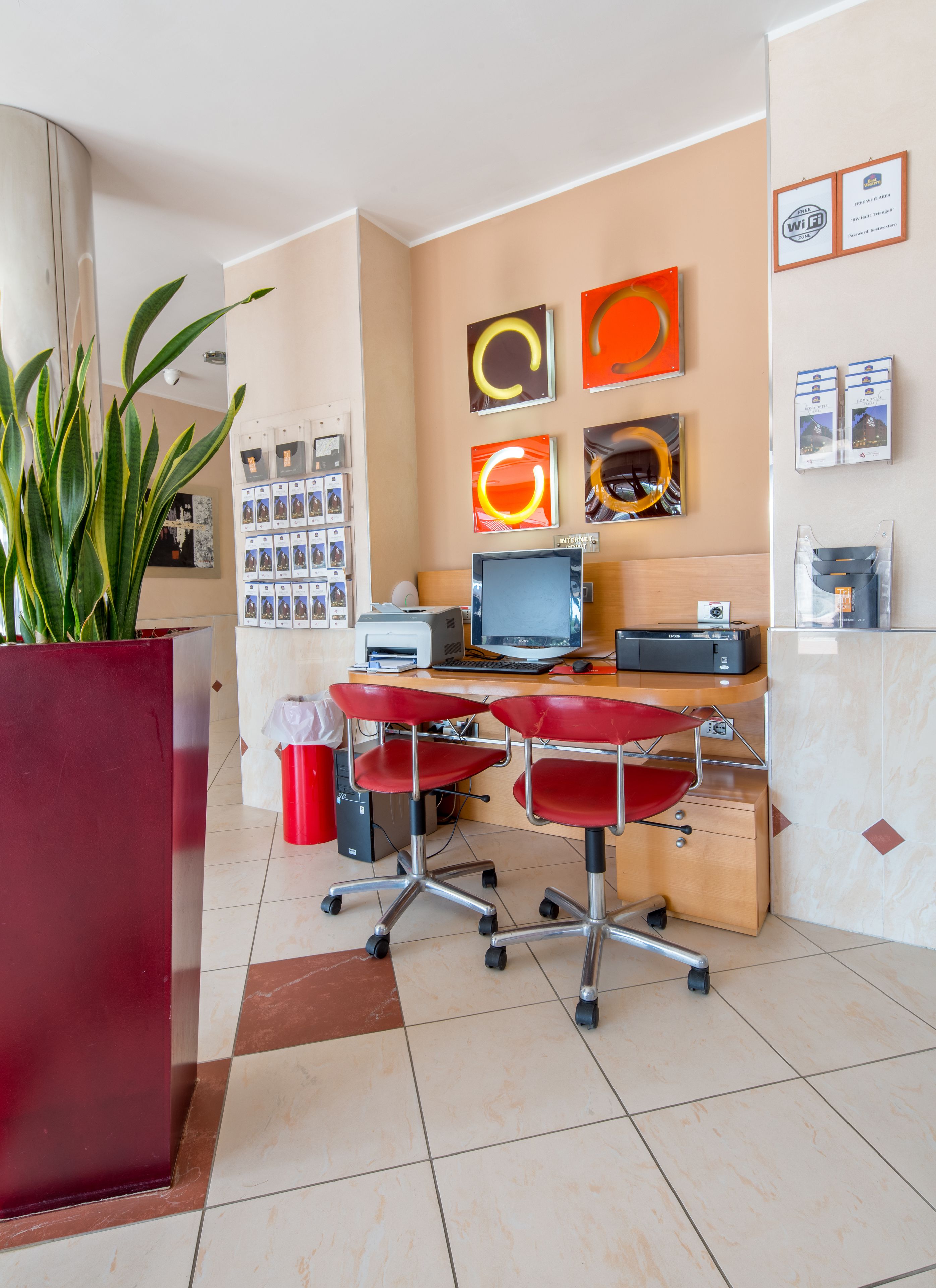A reception area with a desk, computer, printer, and a plant.