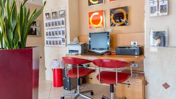 A reception area with a desk, computer, printer, and a plant.