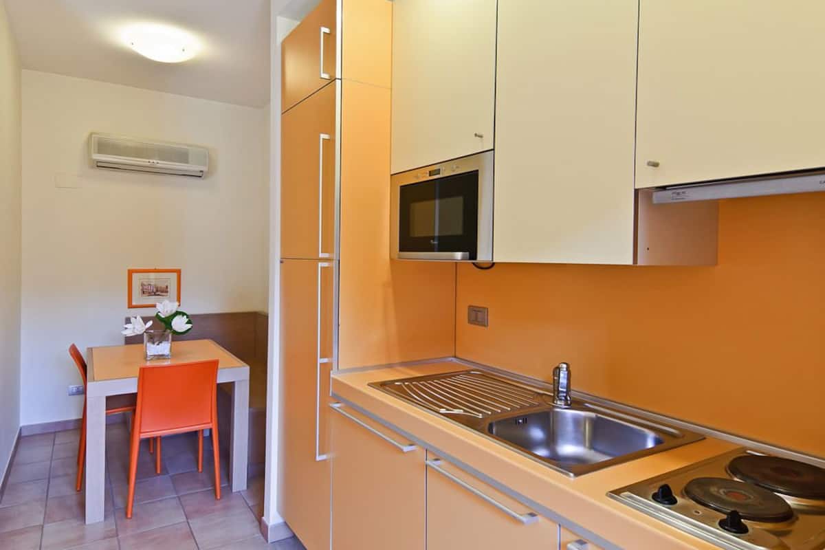 A compact kitchen with a sink, stove, and oven, and a dining area with a table and chair.
