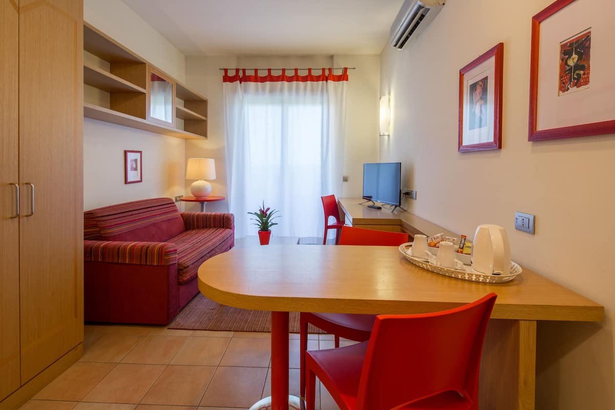 A compact living space with a dining area, a sofa, a TV, and a small plant.