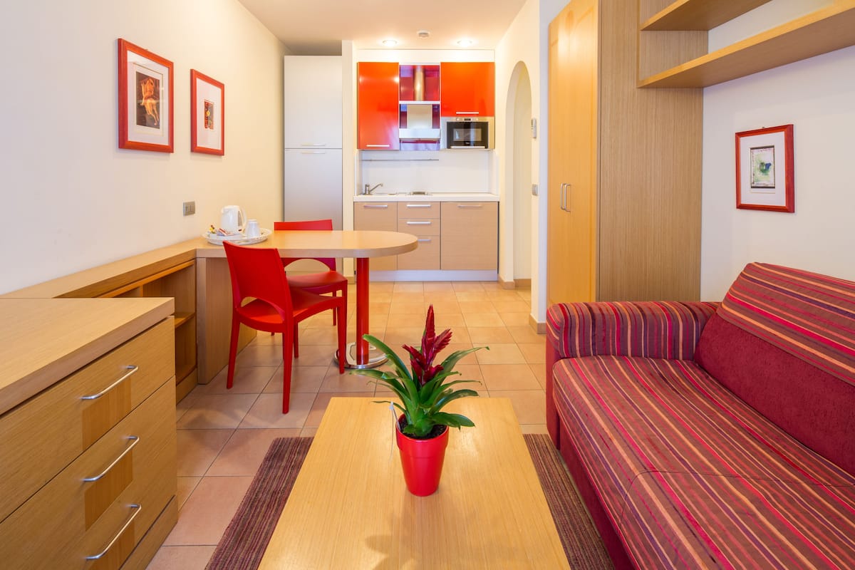 A compact living space with a kitchenette, a dining area, and a sofa.