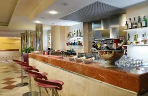 A bar area with a marble countertop, red bar stools, and a large bowl. - I Triangoli Residence (Rome)