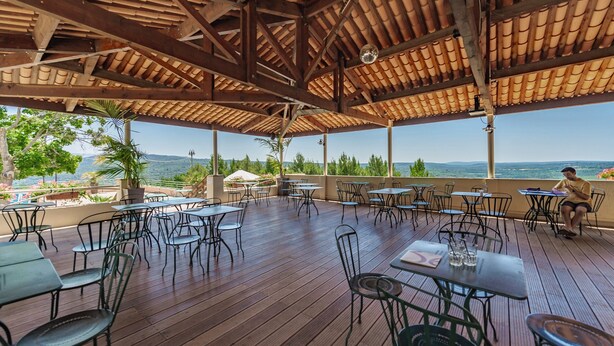 An outdoor patio with wooden flooring, metal chairs, and tables, overlooking a scenic landscape. - Belambra Clubs Montpezat - Le Verdon (Montagnac-Montpezat)